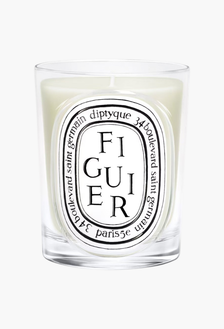 GLAM MODA Diptyque Figuier scented candle in a clear glass jar with a signature oval label and woody fig fragrance.