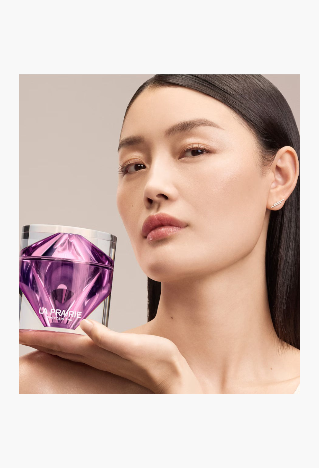 GLAM MODA model holding a luxurious purple La Prairie Platinum Rare Haute-Rejuvenation Cream jar against a white background