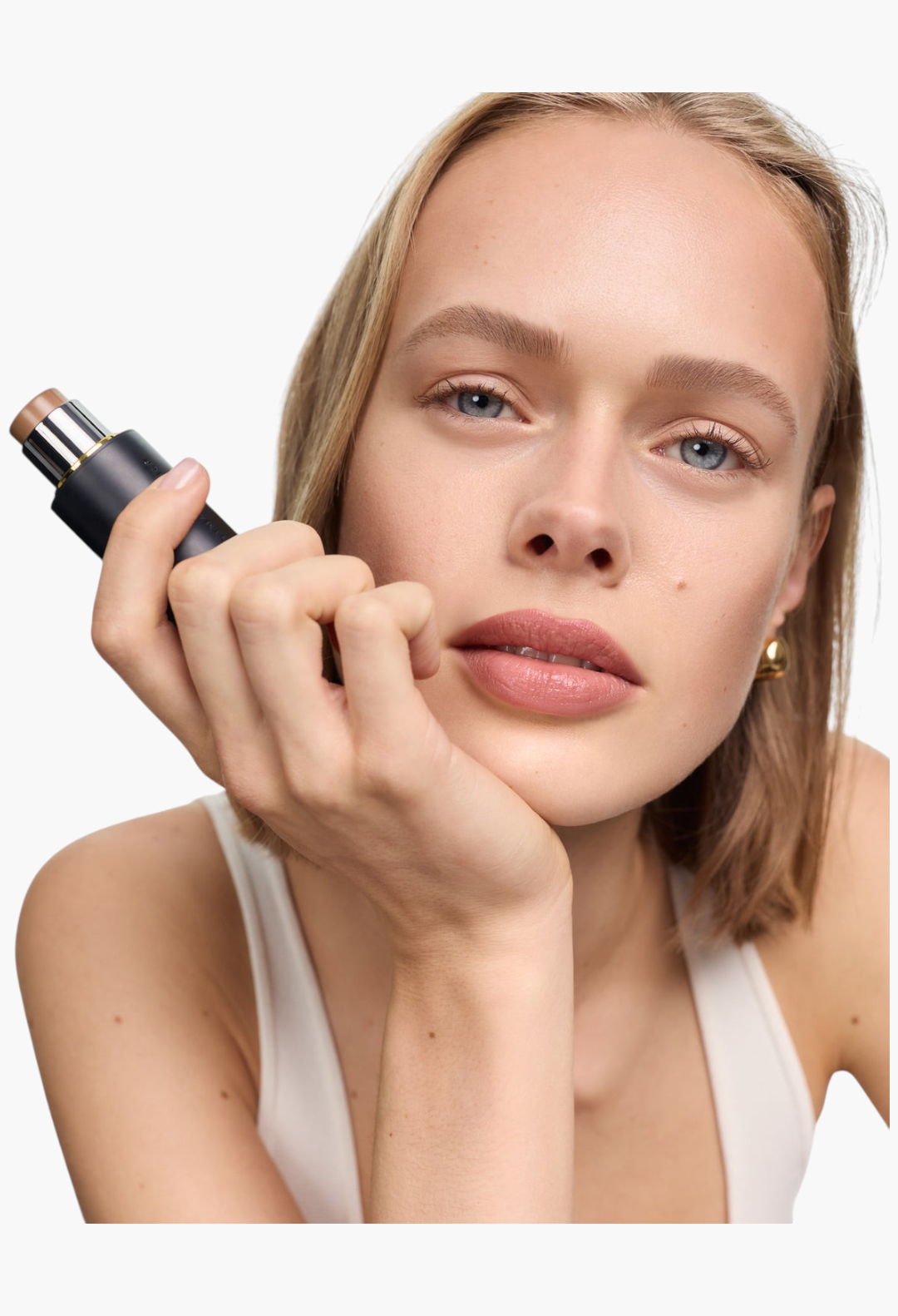 GLAM MODA Face Trace Contour Stick held by a model with natural makeup, showcasing the creamy brown product tip.