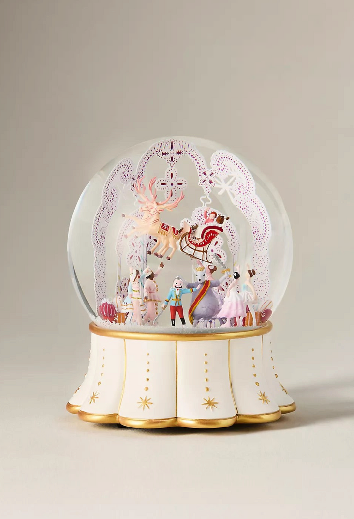 GLAM MODA musical snow globe featuring Nutcracker characters and a reindeer sleigh inside a glass dome on a gold base.