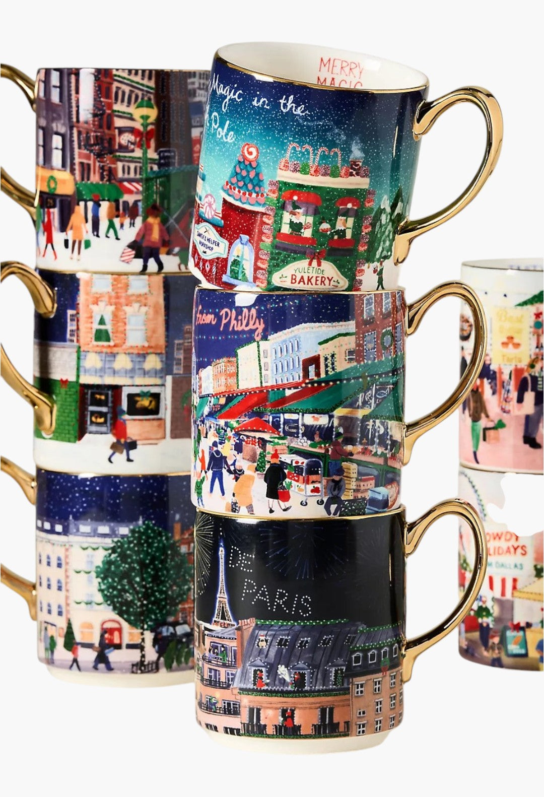 GLAM MODA Holiday in the City stoneware mugs stacked with festive streetscape illustrations and gold-painted handles.
