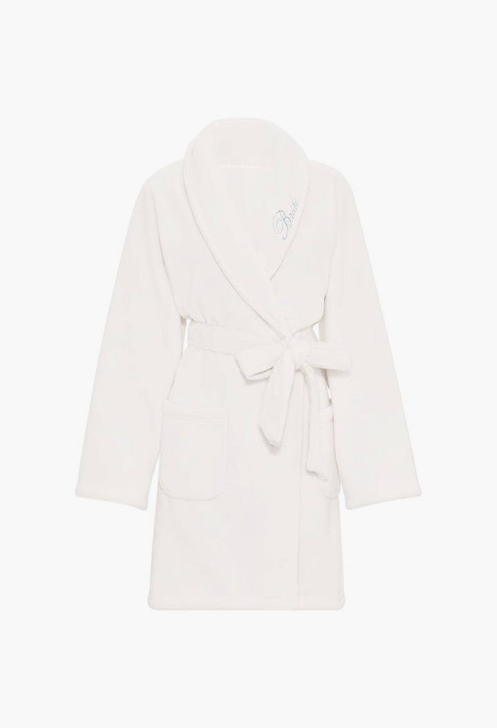 GLAM MODA white plush robe with a shawl collar, tie waist belt, side pockets, and embroidered Bride script detail.