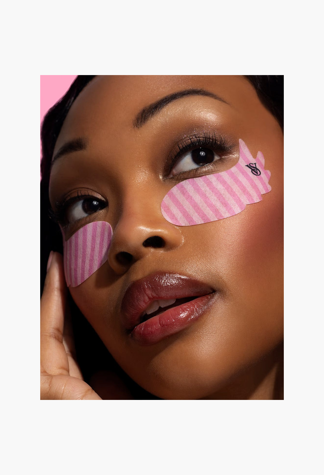 GLAM MODA model wearing pink striped Victoria's Secret x Patchology wing-shaped hydrating undereye patches