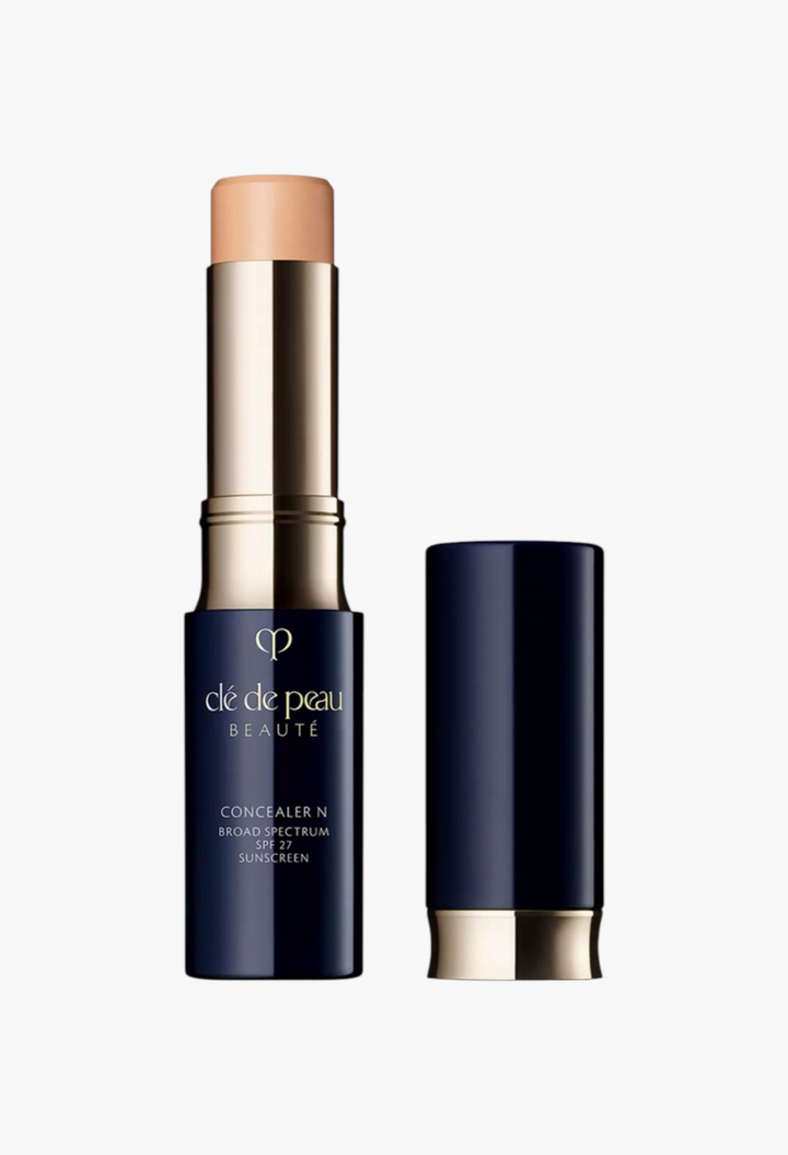 GLAM MODA Clé de Peau Beauté Concealer SPF 27 stick in a navy blue and gold tube with a creamy beige formula.