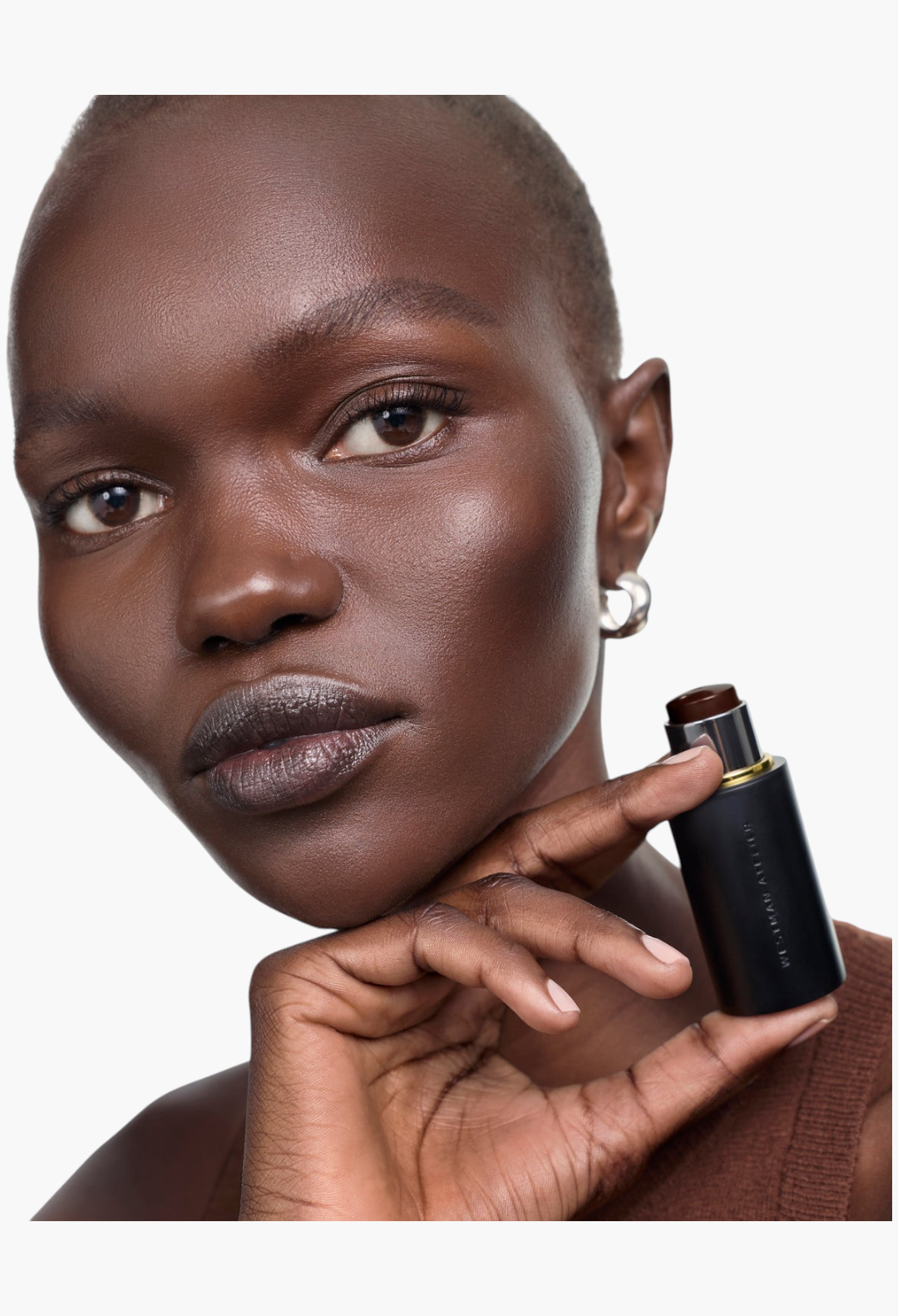 GLAM MODA Face Trace Contour Stick held by a model with glowing skin, showcasing a creamy, blendable makeup formula.