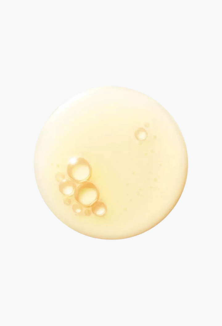 A golden drop of GLAM MODA La Mer The Renewal Oil featuring visible bubbles and a smooth, nourishing texture.