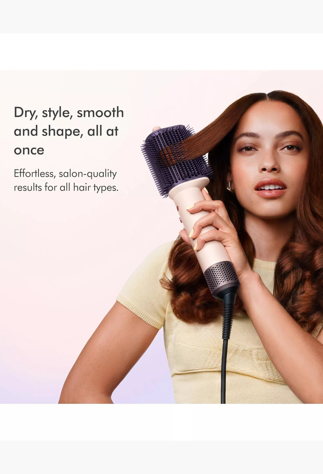 GLAM MODA model using a pink and rose gold Dyson Airsmooth styling brush to smooth a section of her wavy brown hair.
