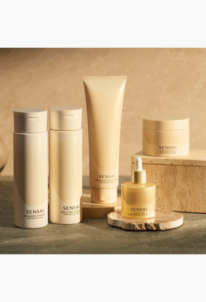 GLAM MODA Sensai scalp and hair care collection featuring bottles, a tube, and a serum dropper on stone pedestals.