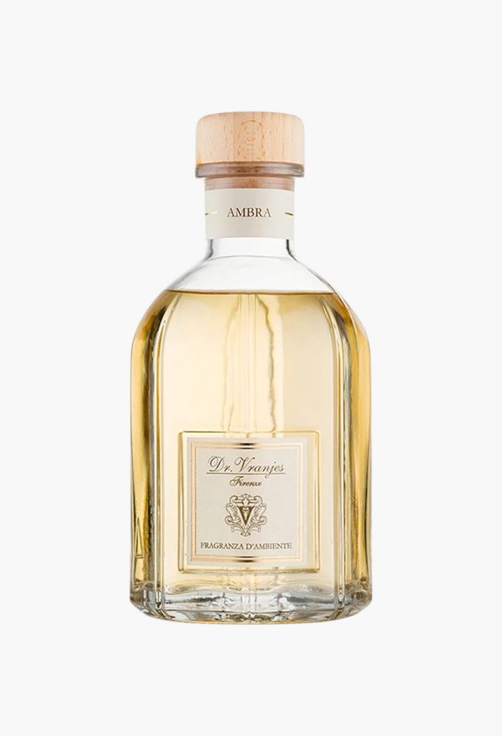GLAM MODA Dr. Vranjes Ambra diffuser in a clear glass bottle with a light wood stopper and amber-toned fragrance oil.