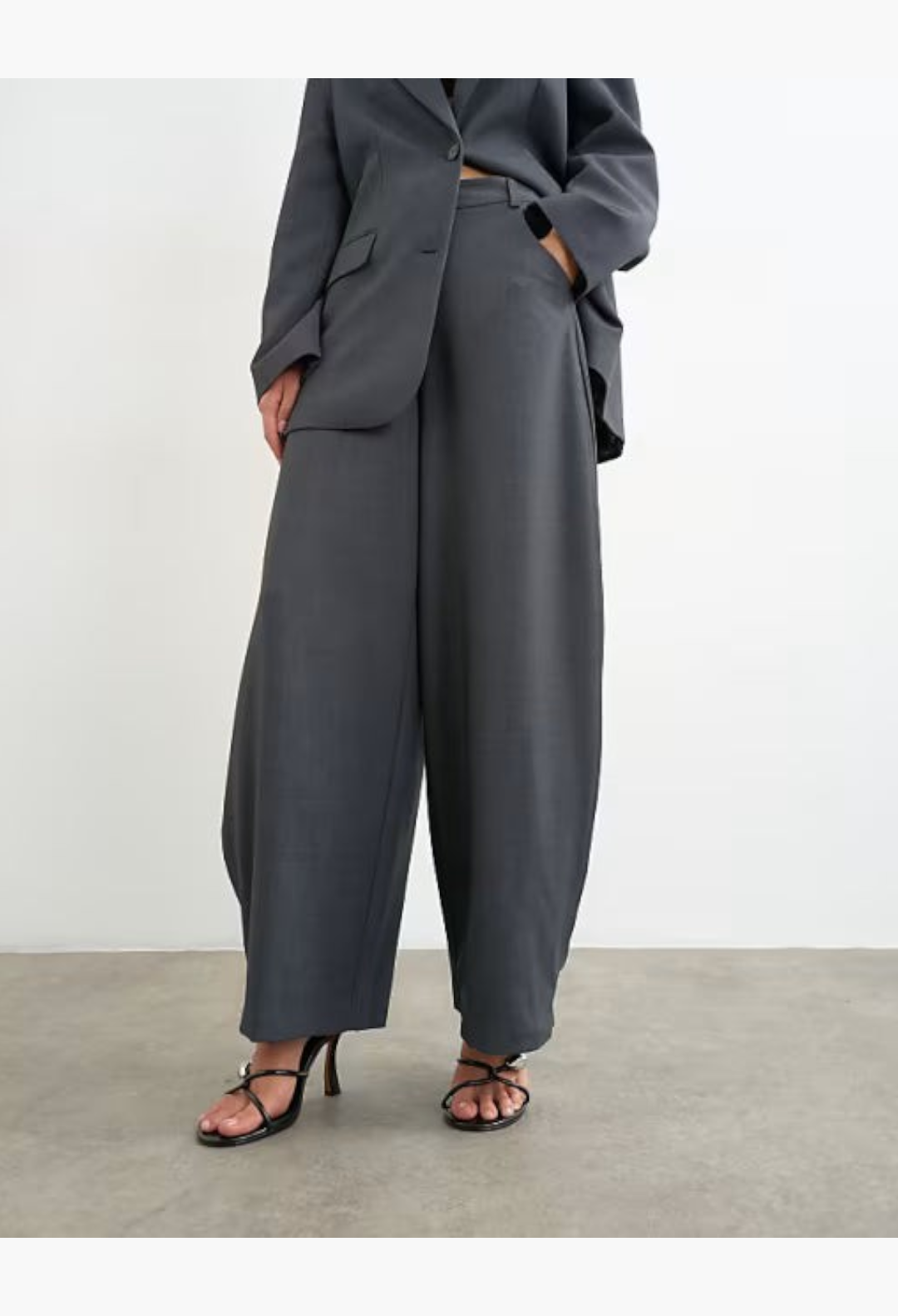 GLAM MODA grey woven trousers with a relaxed barrel leg, side pleats, and mid-rise waist worn with a matching blazer