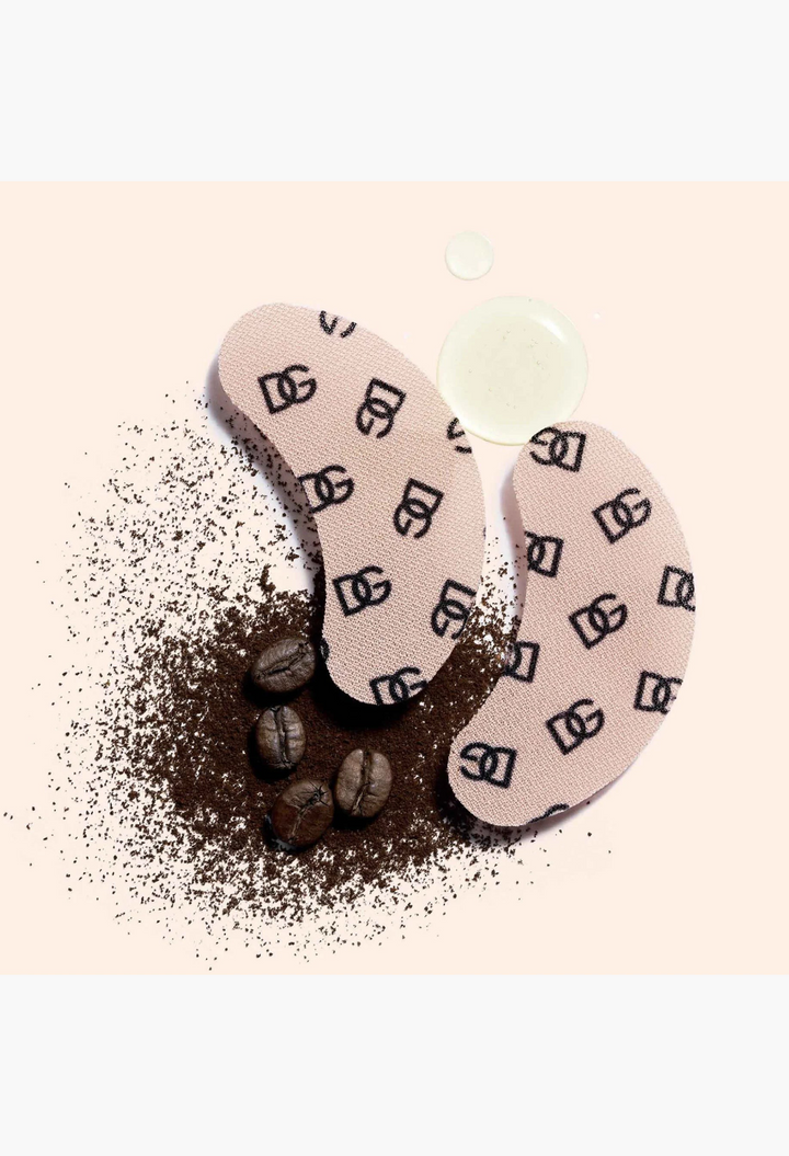 GLAM MODA Dolce & Gabbana caffeine eye patches with DG monogram print, displayed with coffee grounds on white background