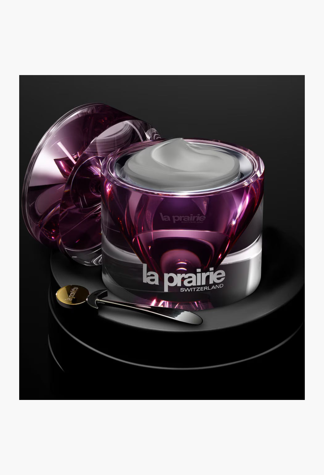 GLAM MODA La Prairie Platinum Rare Haute-Rejuvenation Cream in a purple glass jar with a silver spatula on a black base.