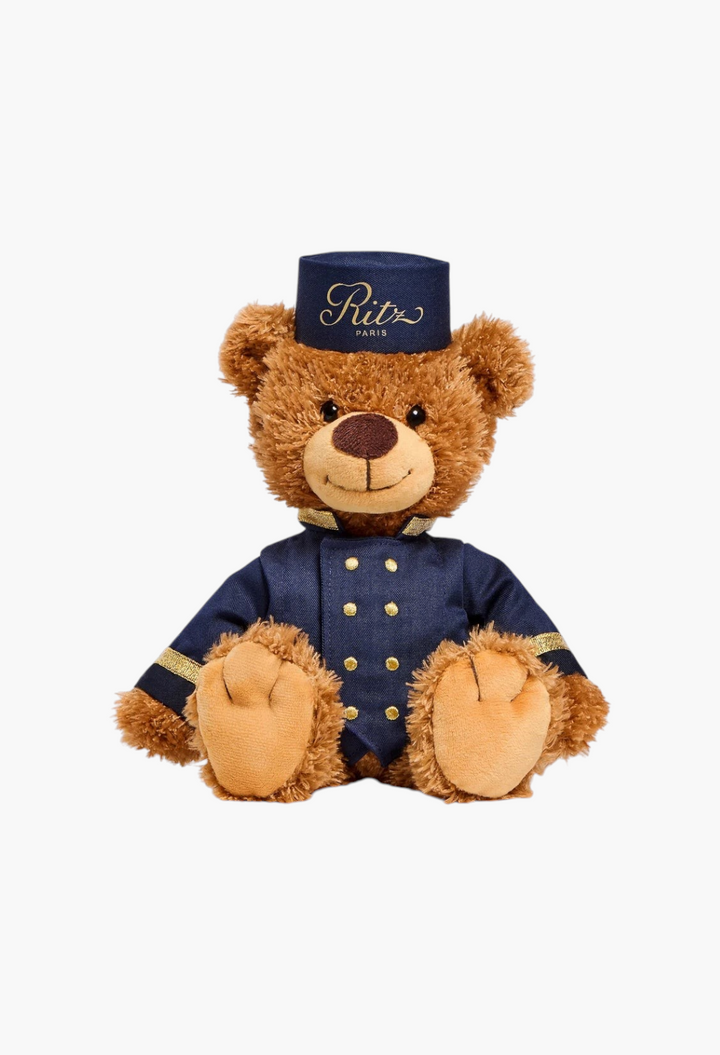 GLAM MODA large brown teddy bear dressed as a Ritz Paris bellboy in a navy blue uniform with gold buttons and hat.