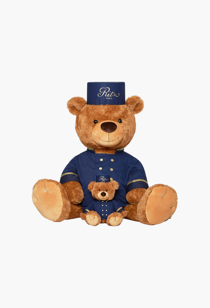 GLAM MODA large and small teddy bears dressed in navy blue Ritz Paris bellboy uniforms with gold button details.