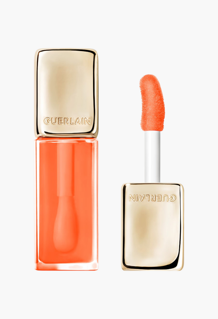 GLAM MODA Guerlain KissKiss Bee Glow Oil in a vibrant orange syrup shade with a gold cap and soft applicator wand.