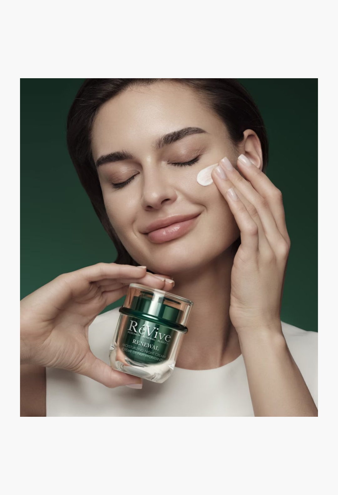 GLAM MODA model applying RéVive Renewal Moisturising Night Cream to her cheek with a radiant, youthful complexion.