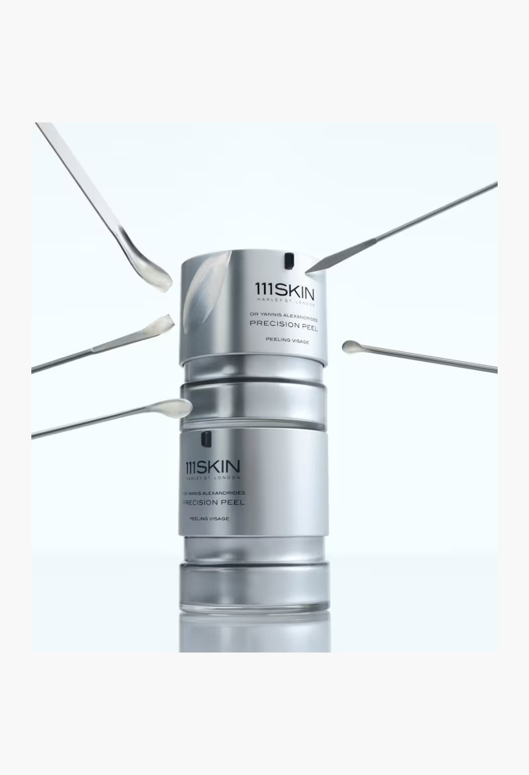 GLAM MODA 111SKIN Precision Peel resurfacing treatment in a silver bottle surrounded by four small applicator spatulas.