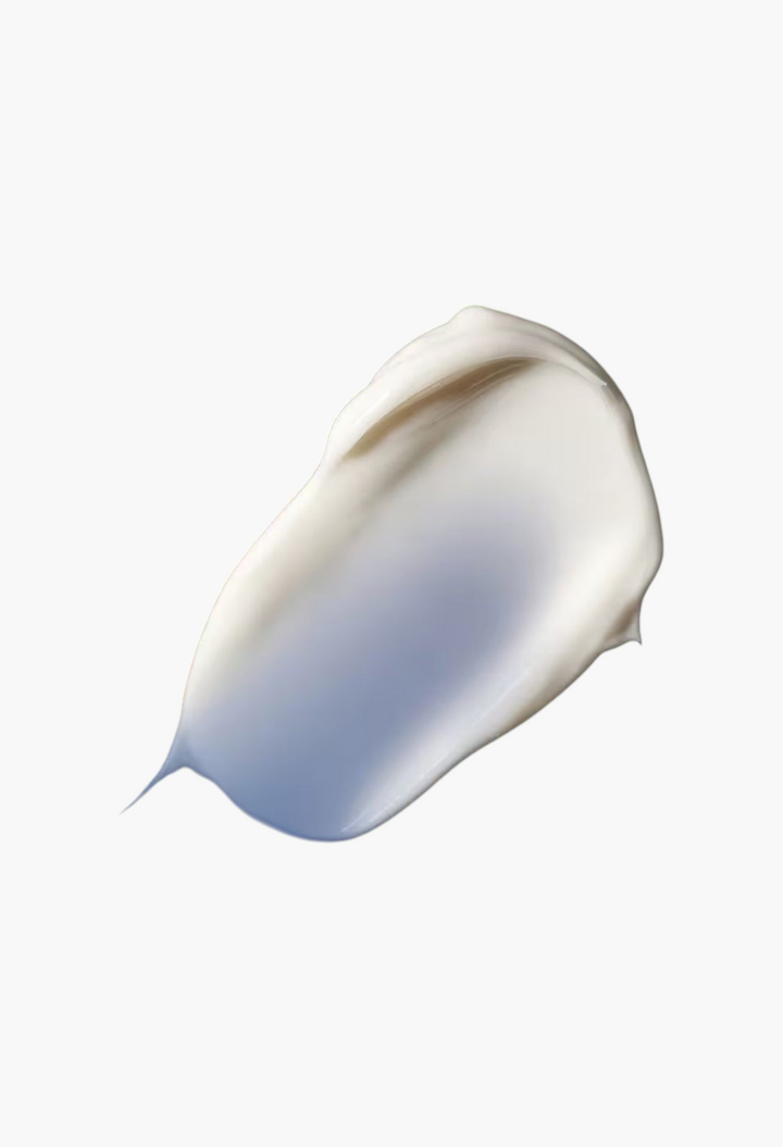 A smooth, rich white cream swatch of GLAM MODA The Overnight Restorative Cream against a deep blue background.