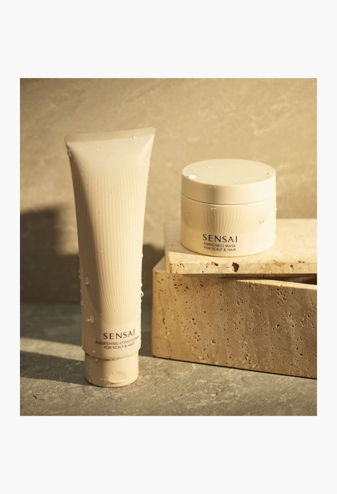 GLAM MODA SENSAI Enriching Mask and Nourishing Conditioner set in beige packaging on a stone pedestal.