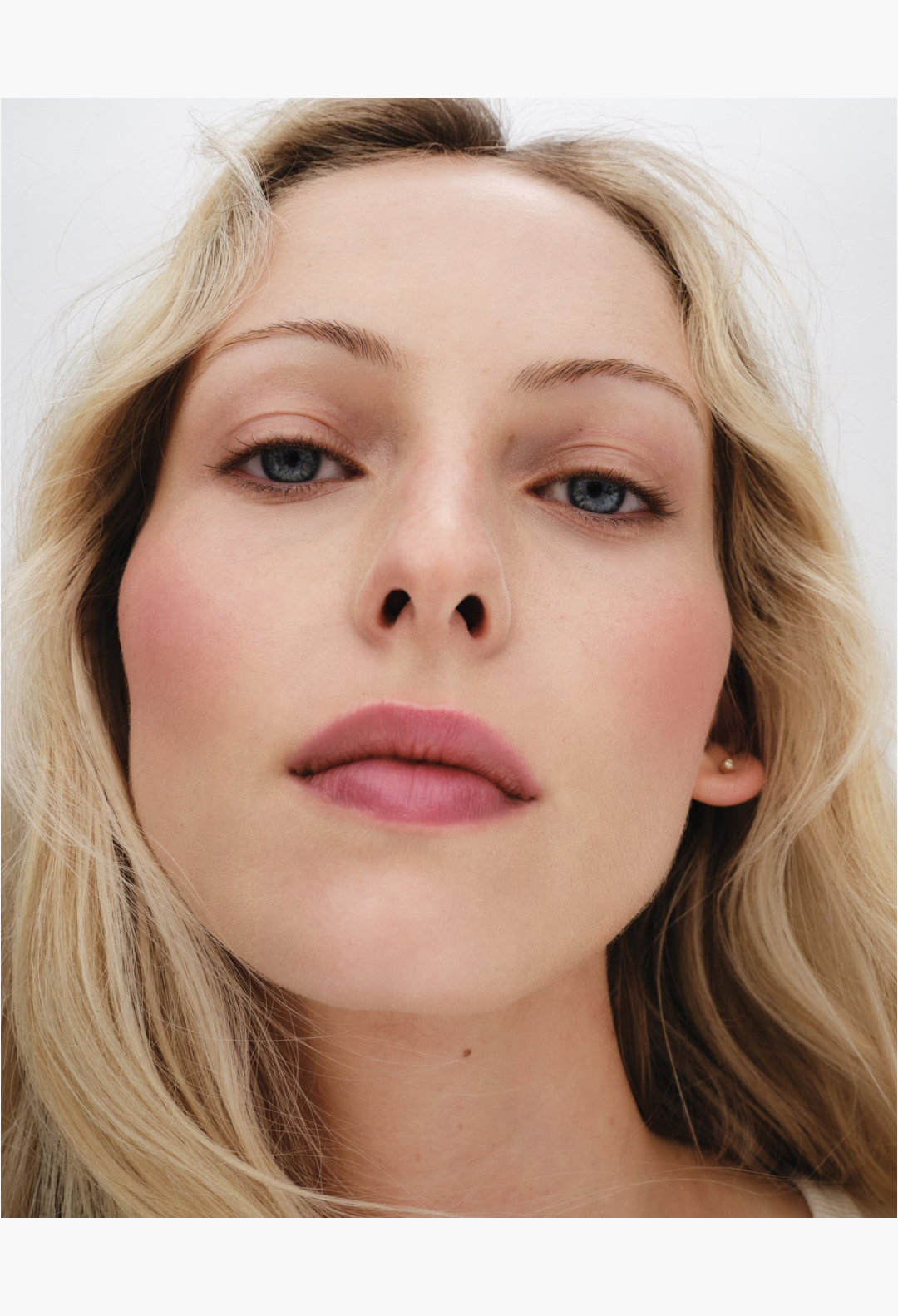 GLAM MODA Baby Cheeks Blush Stick applied to a blonde model's cheeks and lips for a natural flushed look