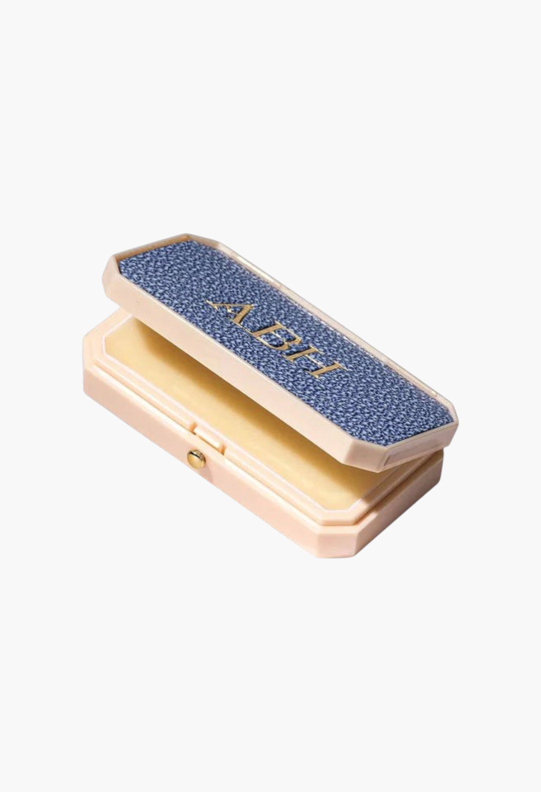 GLAM MODA Baume des Muses Ivory lip balm in a customizable, textured blue and cream case with gold embossed initials.