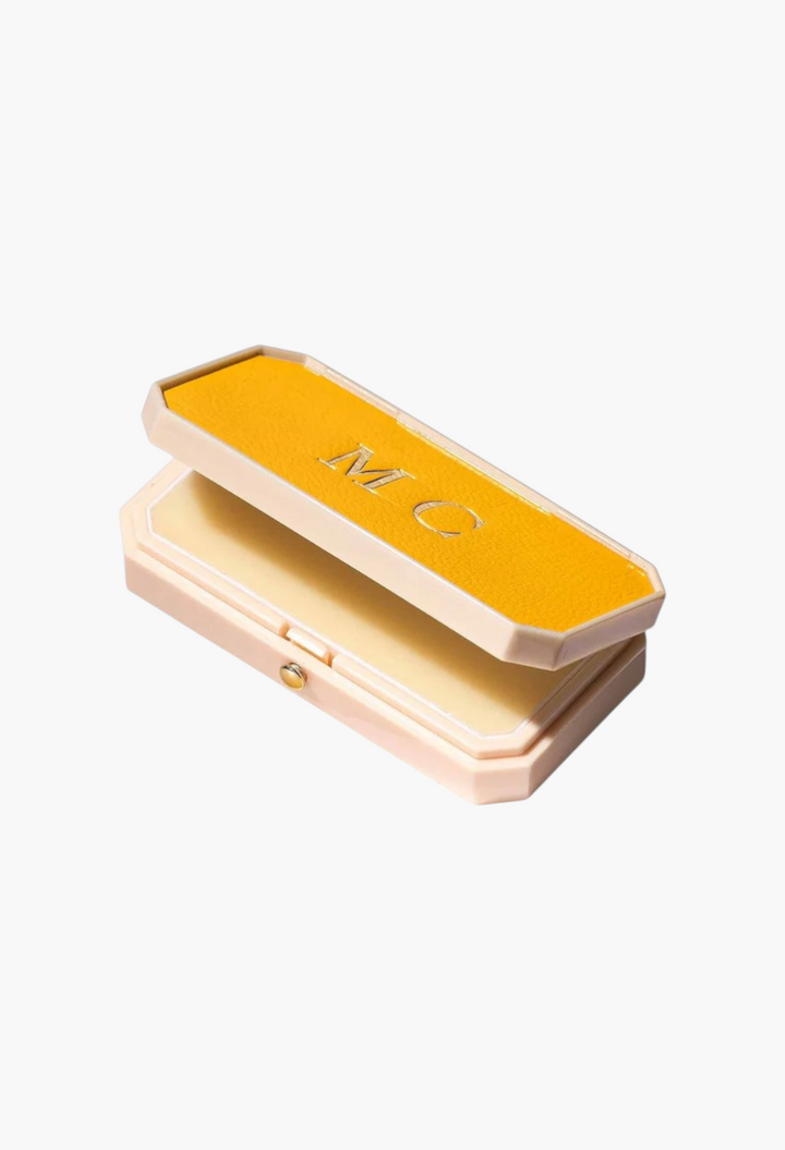 GLAM MODA Baume des Muses Ivory lip balm in a customizable yellow leather-like case with gold embossed initials.