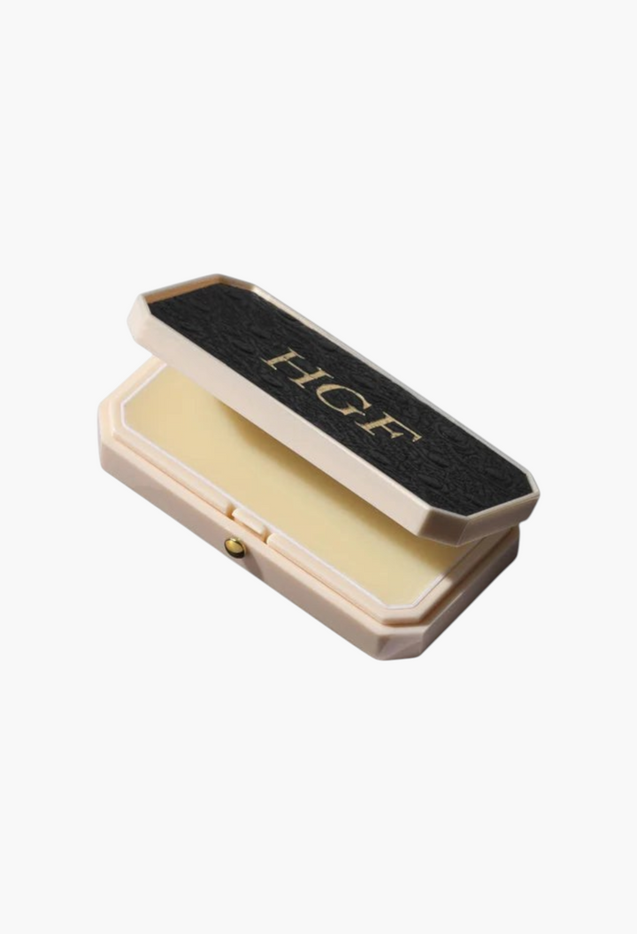 GLAM MODA Baume des Muses Ivory lip balm in an elegant cream and black embossed case with gold initial detailing