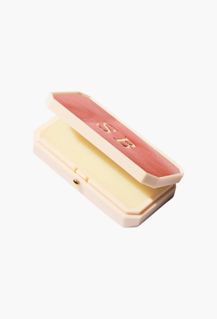 GLAM MODA Baume des Muses Ivory lip balm in a vintage-style rectangular case with a red lid and embossed initials.