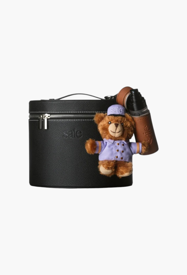GLAM MODA bellhop bear keychain attached to a black leather vanity case with a brown leather bottle holder