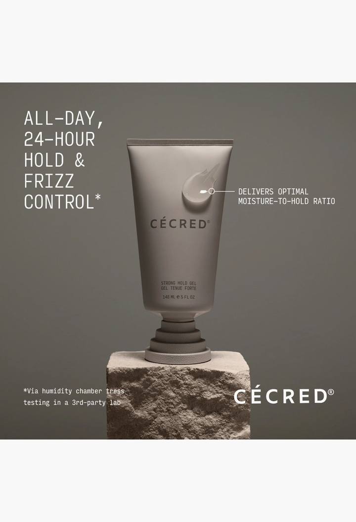 GLAM MODA Strong Hold Gel in a grey tube on a stone pedestal, featuring 24-hour hold and frizz control benefits.