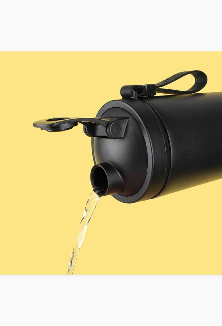 GLAM MODA Matte Shaker stainless steel water bottle in black pouring water against a yellow background
