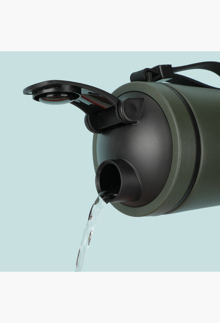 GLAM MODA Matte Shaker in olive green pouring water from its open vacuum-seal cap against a light blue background