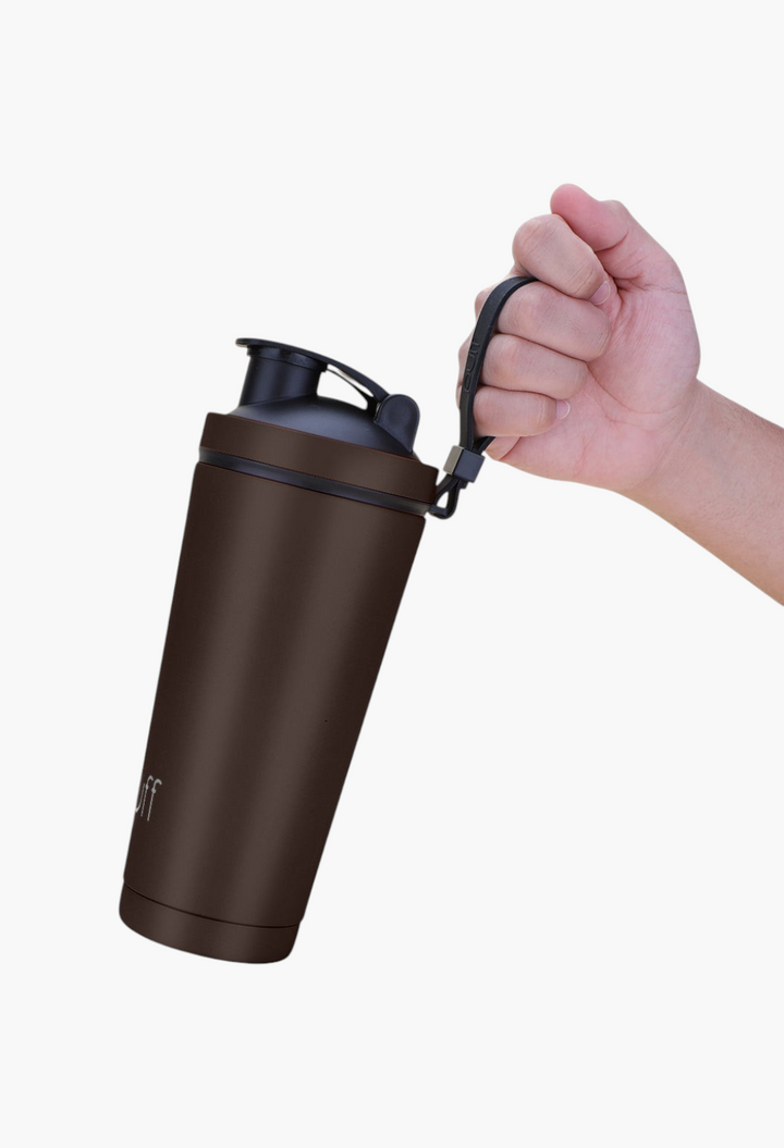 GLAM MODA matte brown stainless steel insulated shaker bottle with a black lid and carrying strap held by a hand