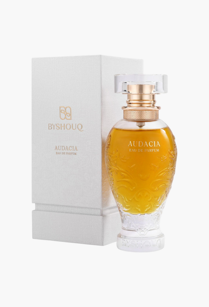 GLAM MODA Audacia woody eau de parfum in an ornate glass bottle with gold accents next to its white textured box.