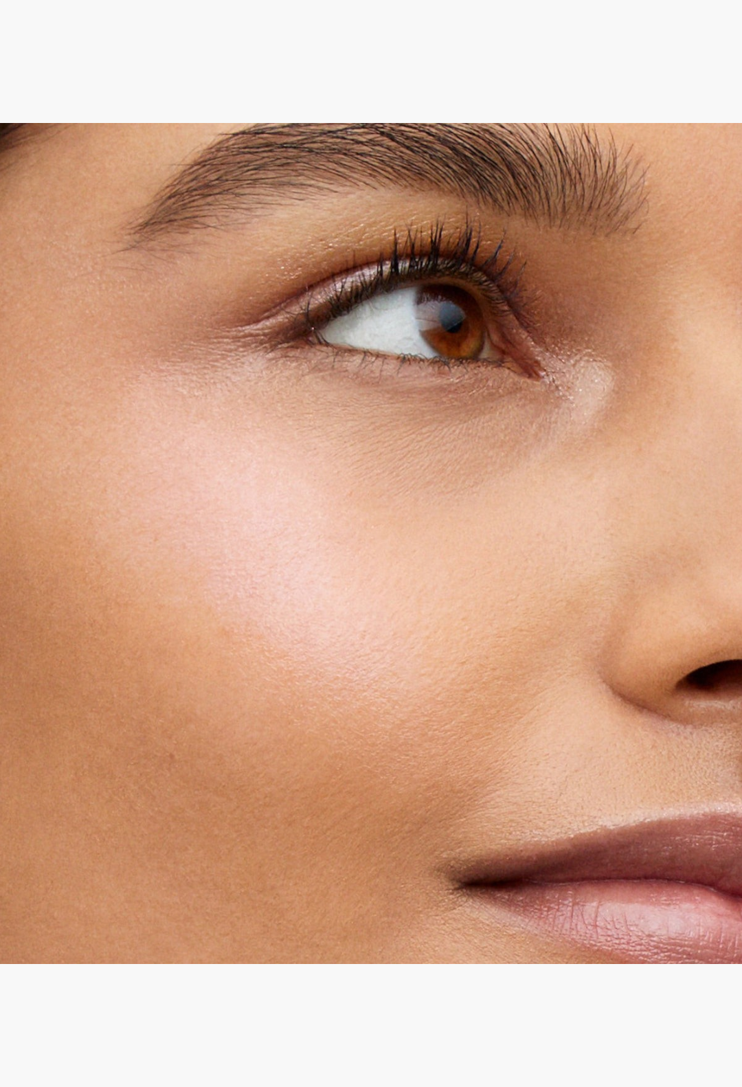 GLAM MODA Lit Up Highlight Stick applied to cheekbones for a radiant glassy finish on a model