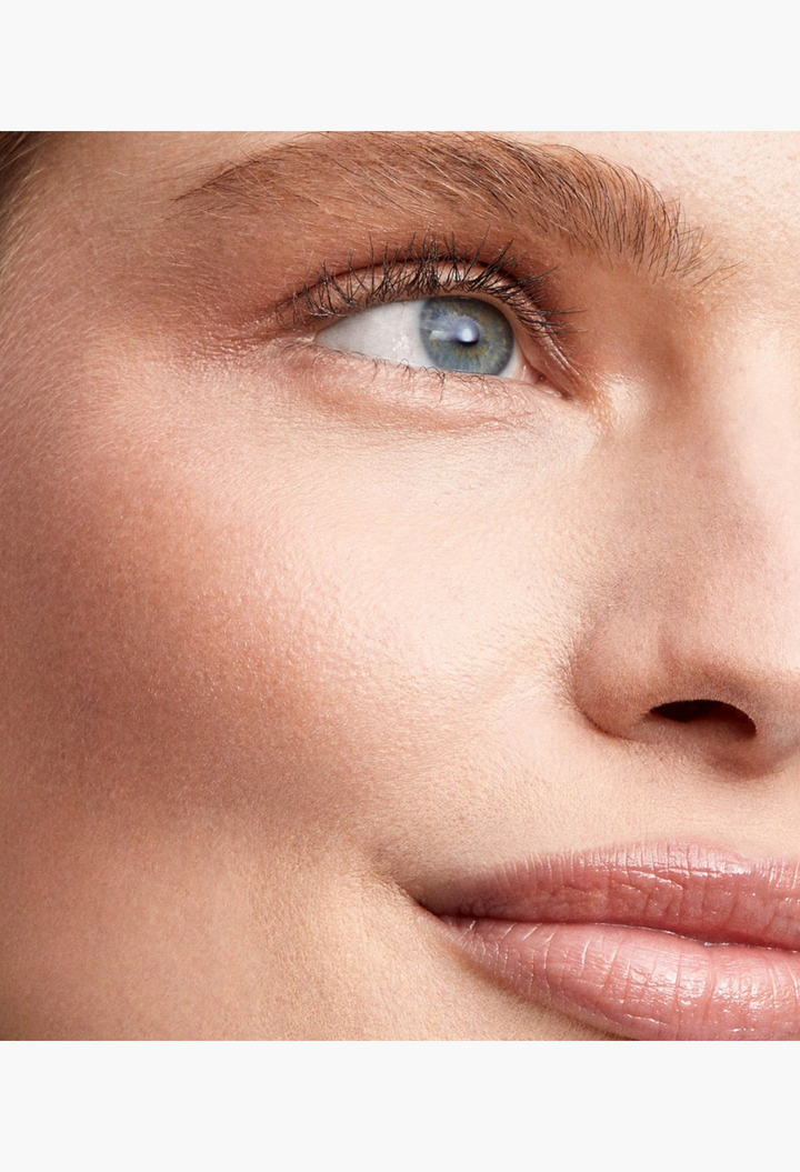 GLAM MODA Lit Up Highlight Stick applied to a model's cheekbone and eyelid for a radiant, glassy finish