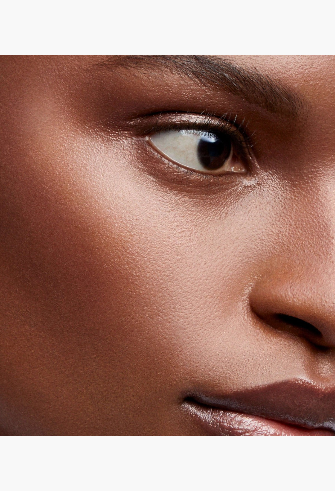 GLAM MODA Lit Up Highlight Stick applied as a translucent gel on a model's cheekbone and nose for a glassy finish.