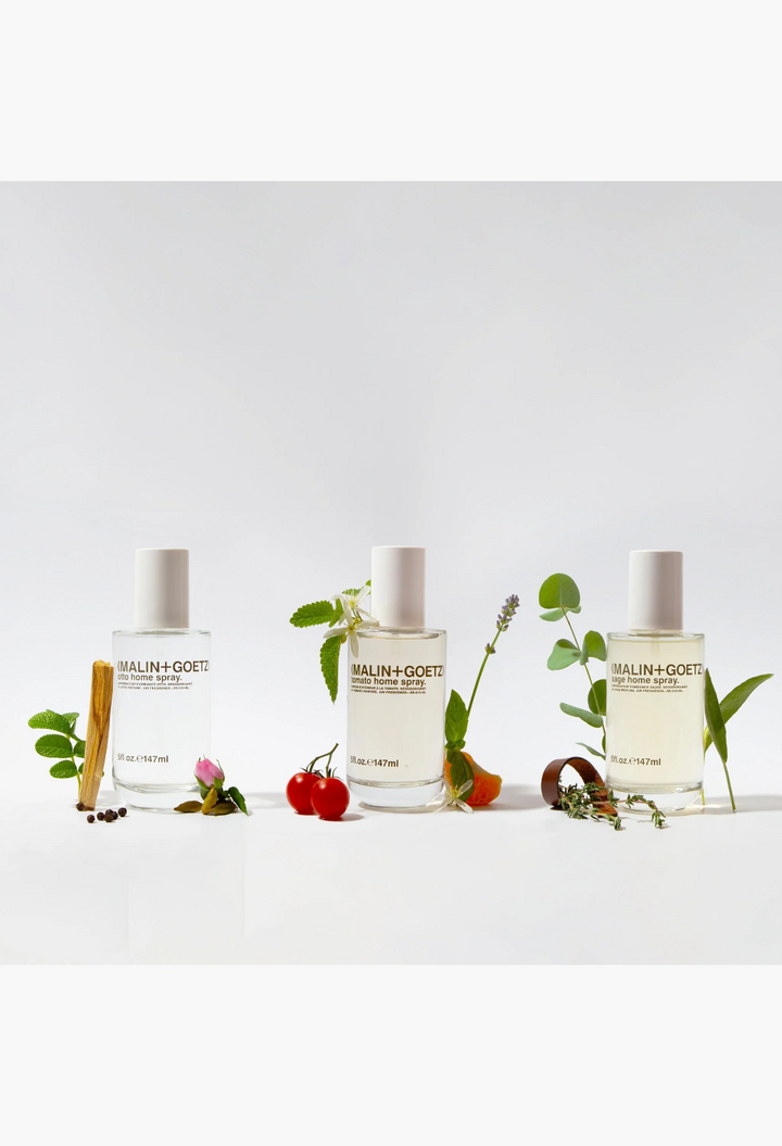 GLAM MODA Malin + Goetz tomato home spray bottle with fresh tomatoes and herbs on a white background