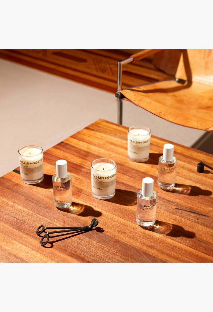 GLAM MODA collection of Malin + Goetz tomato home sprays and candles with a black metal wick trimmer on white background