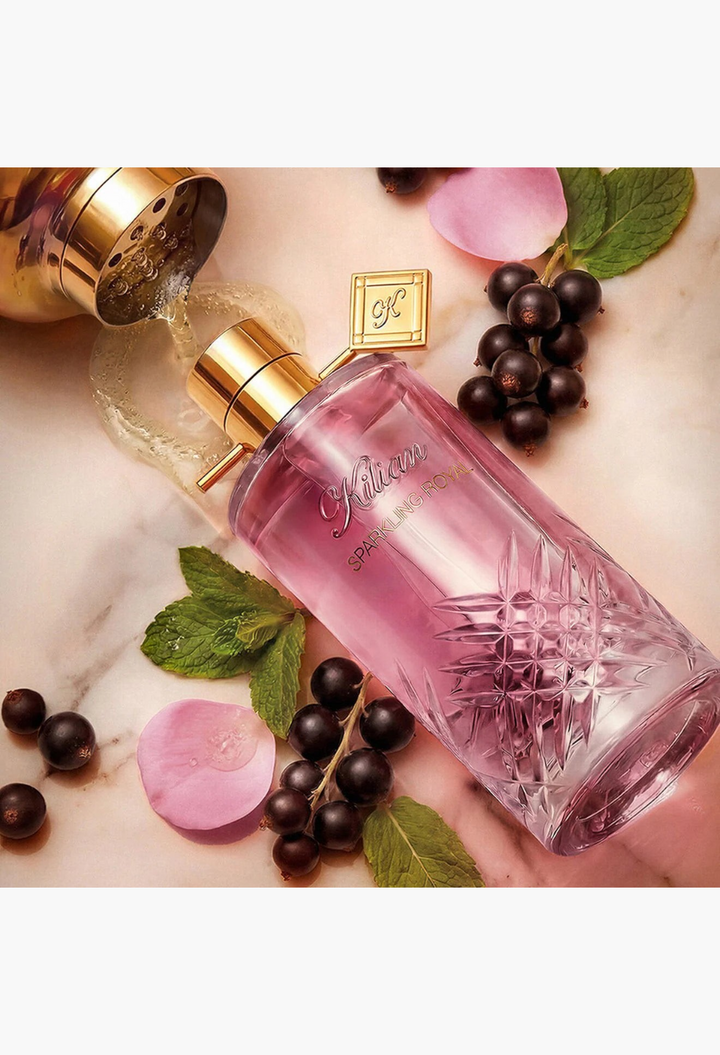 GLAM MODA Sparkling Royal Eau De Parfum bottle with pink liquid, surrounded by blackcurrants, mint leaves, and petals.