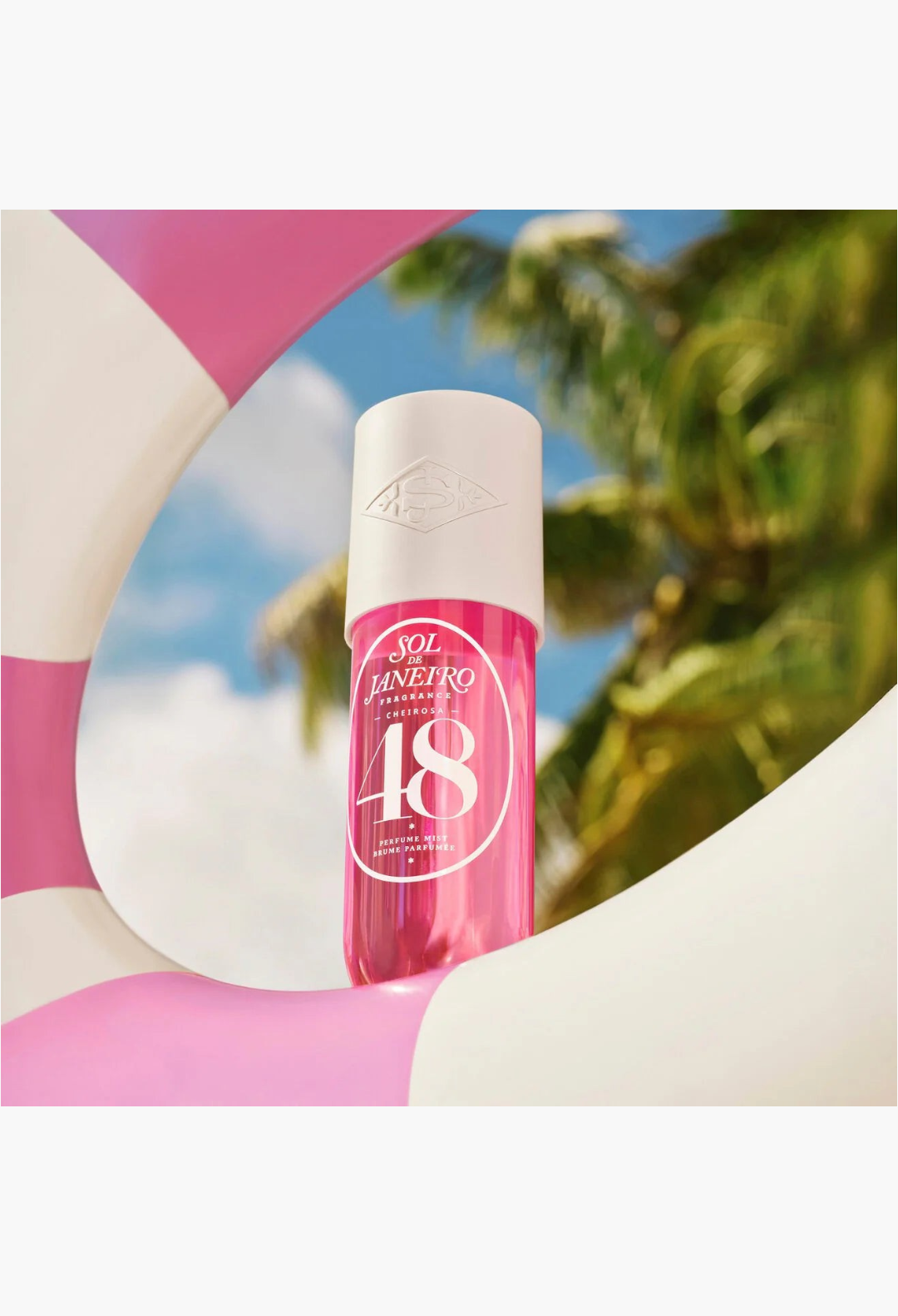 GLAM MODA Cheirosa 48 perfume mist in a pink bottle framed by a pink and white pool float against a tropical backdrop.