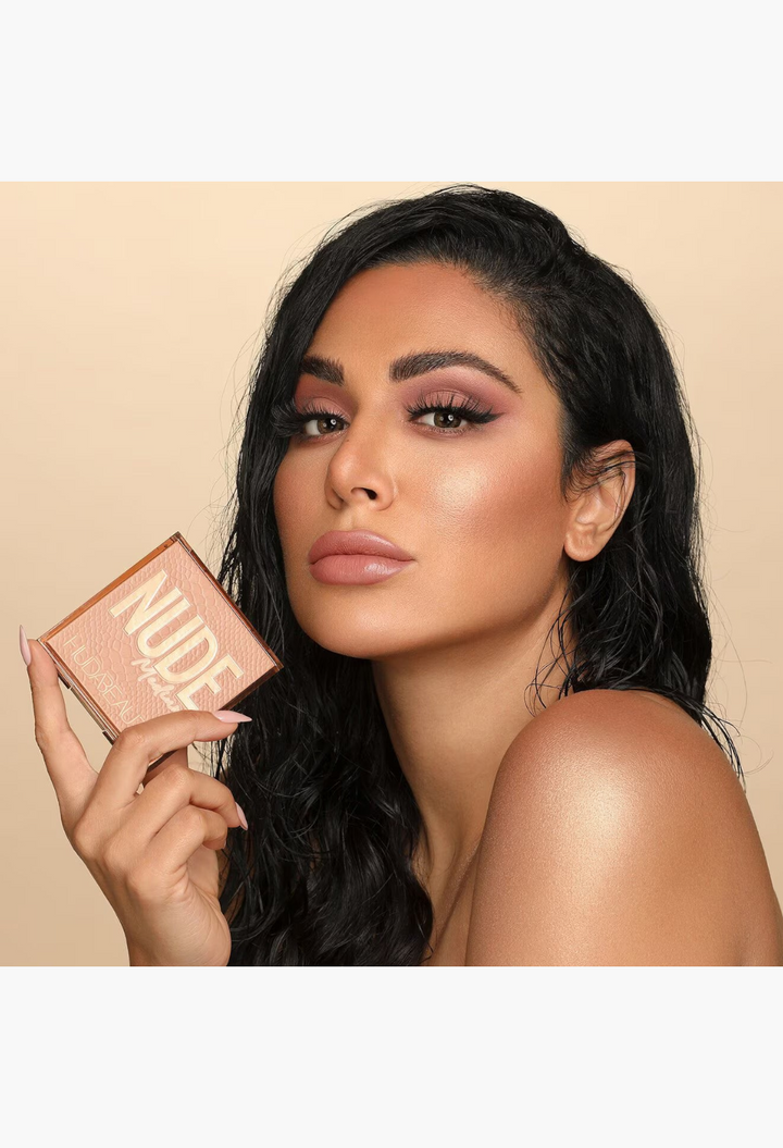 GLAM MODA model holding a Nude Obsessions eyeshadow palette with a soft glam makeup look featuring warm neutral tones.