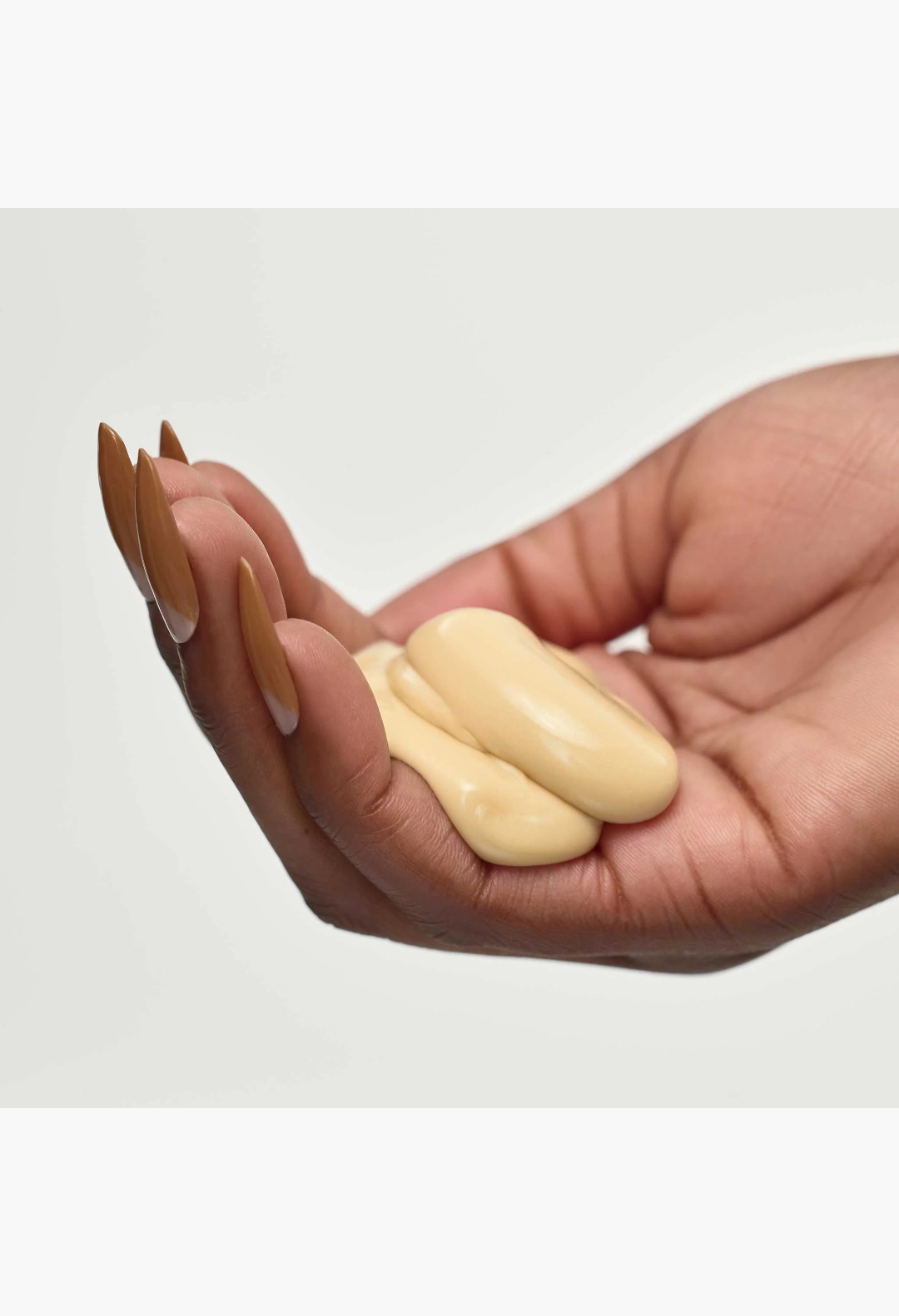 GLAM MODA Reconstructing Treatment Mask cream texture held in a hand with long brown nails