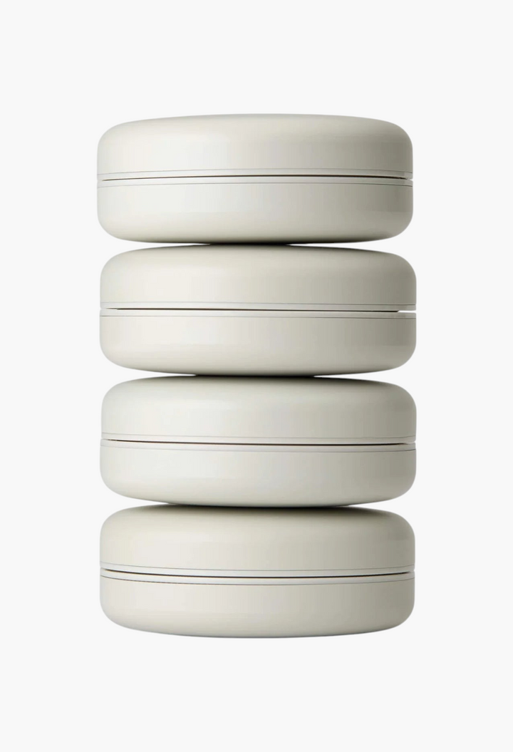 GLAM MODA Le Balm Quatre set of four unscented solid serum compacts stacked vertically on a white background.
