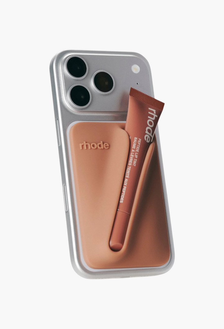 GLAM MODA snap-on silicone lip case in bronze attached to a silver iPhone with a peptide lip treatment tube