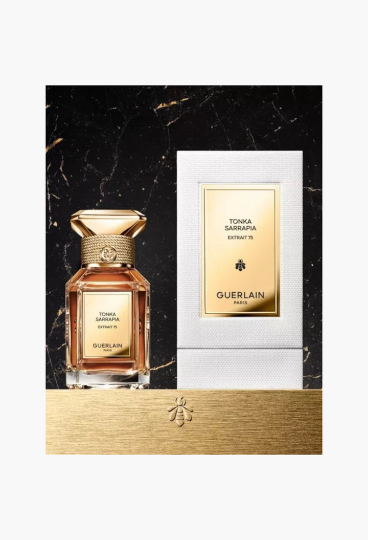 GLAM MODA Guerlain Tonka Sarrapia Extrait 75 perfume bottle and white box on a black marble surface with gold accents