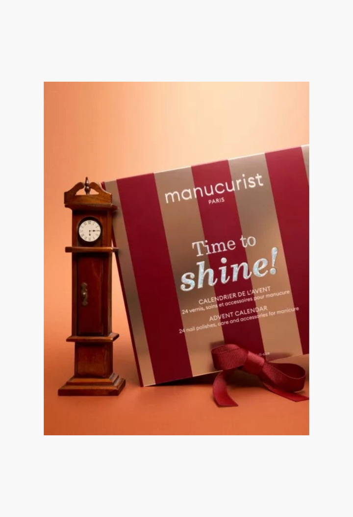 GLAM MODA Manucurist Time to Shine! Advent Calendar with red and gold stripes next to a miniature grandfather clock.