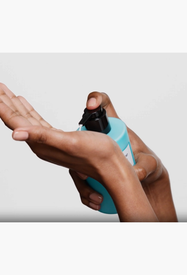 GLAM MODA Portofino '97 body lotion in a Ligurian blue bottle being dispensed into hands for application.