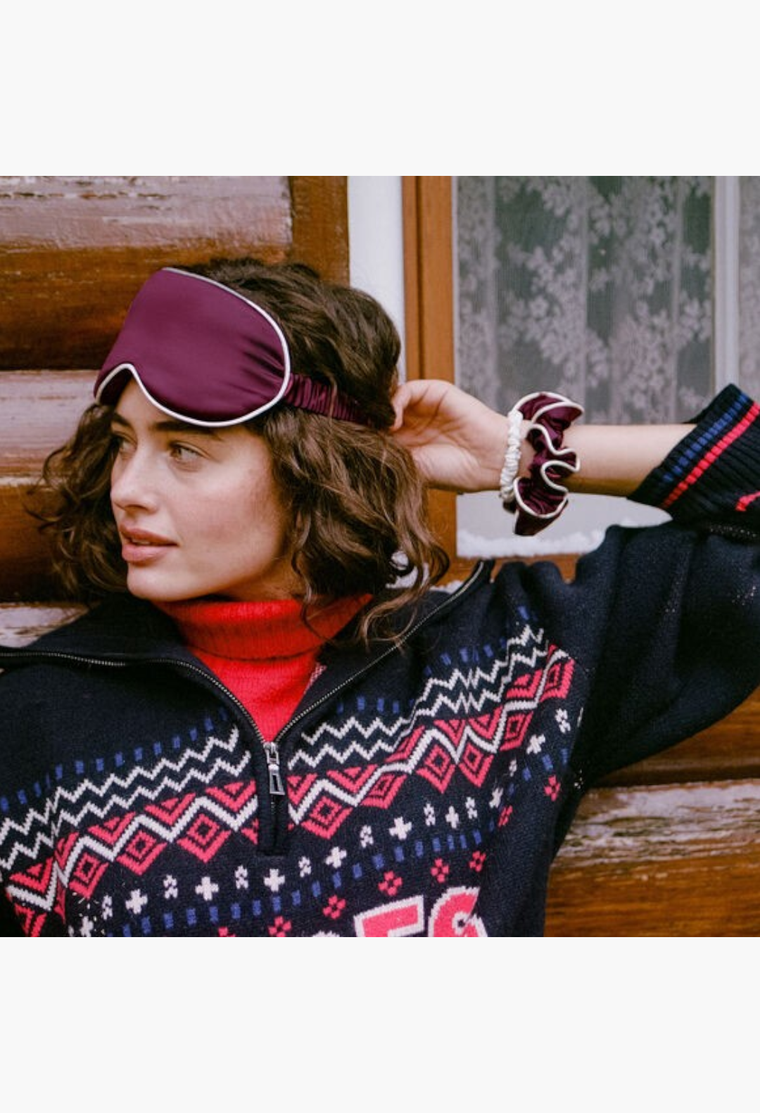 GLAM MODA silk sleep mask and scrunchie set in crimson and white worn by a woman in a patterned sweater