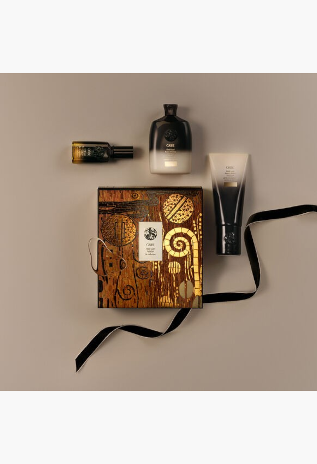 GLAM MODA Oribe Gold Lust haircare set featuring shampoo, conditioner, and hair oil in a decorative gift box.